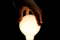 Man's hand on illuminated light bulb by Sami Sarkis Photography