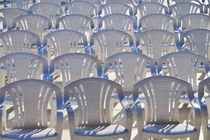 Rows of empty white plastic chairs by Sami Sarkis Photography