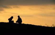 Silhouette of a squatting couple at sunset by Sami Sarkis Photography
