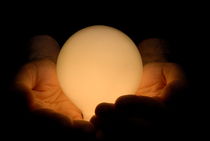 Man with hands cupped around illuminated light bulb von Sami Sarkis Photography
