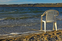 Plastic chair on water edge on beach by Sami Sarkis Photography