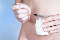 Naked woman holding spoon and yoghurt by Sami Sarkis Photography