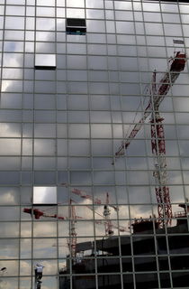 Construction cranes reflected in glass office building by Sami Sarkis Photography