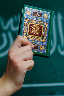 Boy's hand holding Koran by Sami Sarkis Photography