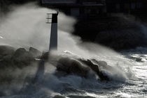 Waves breaking against rocks and beacon by Sami Sarkis Photography