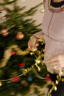 Woman decorating Christmas tree by Sami Sarkis Photography