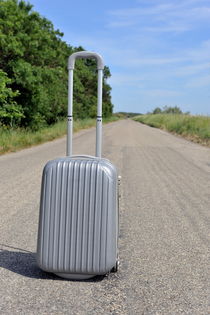 Suitcase on empty countryside road by Sami Sarkis Photography