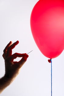 Man's hand with pin next to balloon by Sami Sarkis Photography