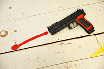 Toy gun on floor with red paint von Sami Sarkis Photography