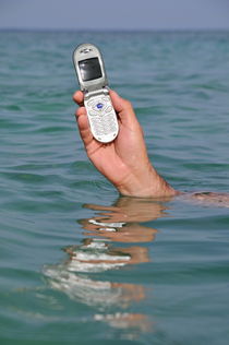 Man's hand holding cellphone out of sea surface by Sami Sarkis Photography