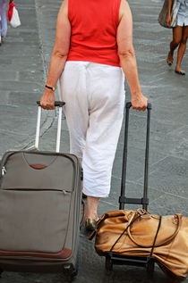 Senior woman pulling luggages on streets by Sami Sarkis Photography