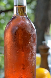 Fresh bottle of Rose wine on table by Sami Sarkis Photography