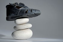 Baby shoe on stack of pebbles by Sami Sarkis Photography