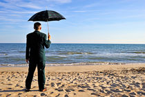 Businessman with umbrella on beach by Sami Sarkis Photography