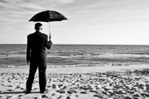 Businessman with umbrella on beach by Sami Sarkis Photography