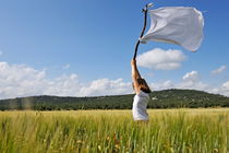 Girl holding high a white flag in wheat field by Sami Sarkis Photography
