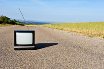 Old fashioned TV on empty countryside road by Sami Sarkis Photography