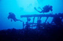 Scuba divers exploring a shipwreck. by Sami Sarkis Photography