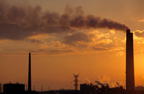 Silhouetted smoking chimney at sunset by Sami Sarkis Photography