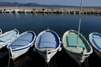 Small fishing boats lined up in a near row by Sami Sarkis Photography