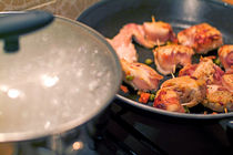 Bacon wrapped around chicken with toothpicks being grilled in a frying pan. von Sami Sarkis Photography
