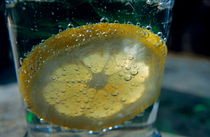 Lemon slice floating in a fizzy drink. by Sami Sarkis Photography