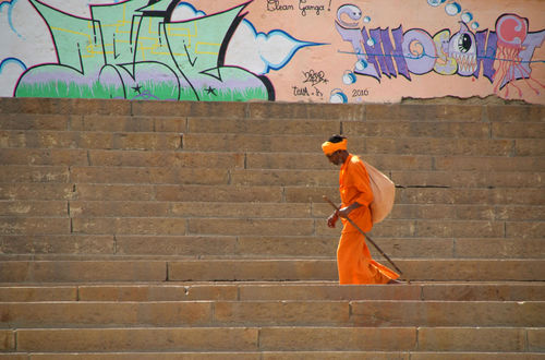 Saddhu-walking-on-ghats-with-graffiti-in-backgroung