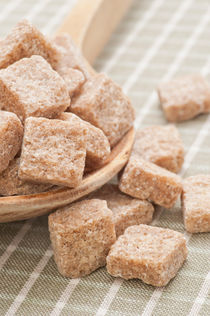 Brown sugar cubes on a wooden spoon by Lars Hallstrom