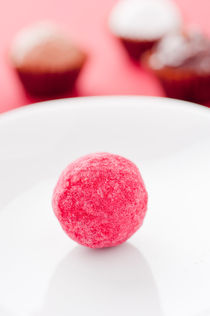 Closeup of a red chocolate truffle on a white plate by Lars Hallstrom