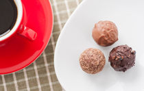 Three chocolate truffles and a red coffee cup by Lars Hallstrom