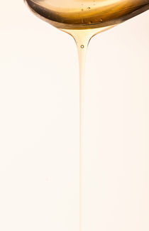 Honey dripping from spoon by Lars Hallstrom